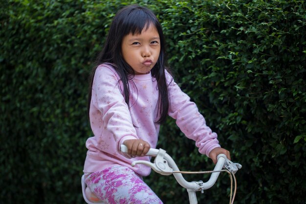 Portrait of a happy cheerful asian child girl riding a bicycle