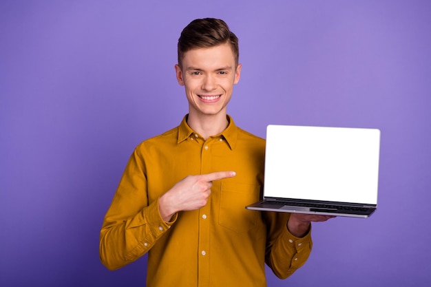 Portrait of happy cheerful man pointing screen laptop computer looking camera isolated over shine background