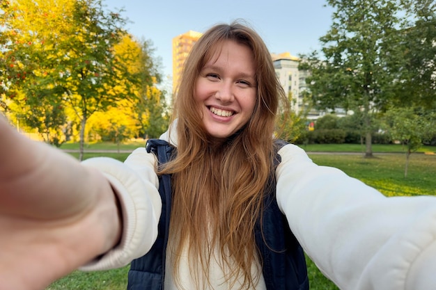 Portrait of happy cheerful young beautiful woman walking outdoors at summer or golden autumn park