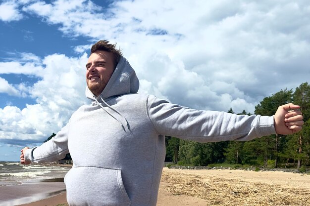 Portrait of happy cheerful young man walk outdoors on the beach at summer or autumn day relax have