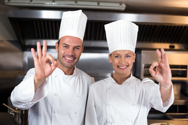 Il ritratto dei cuochi unici felici che mostrano bene firma dentro la cucina