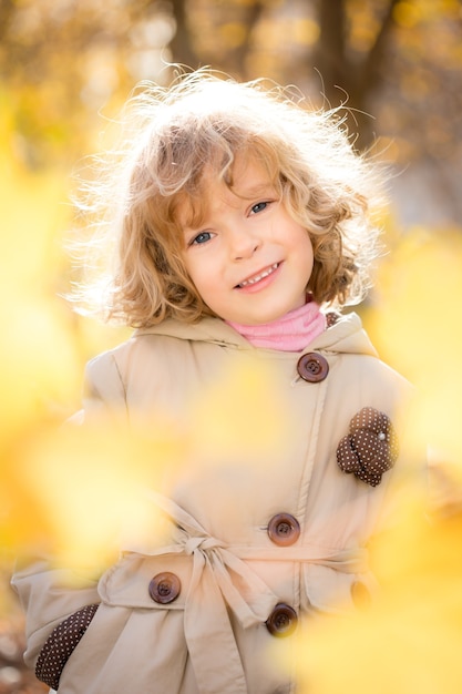 Портрет счастливого ребенка осенью. Рамка из золотых кленовых листьев