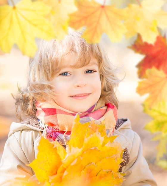 Portrait of happy child in autumn. Frame of golden maple leaves