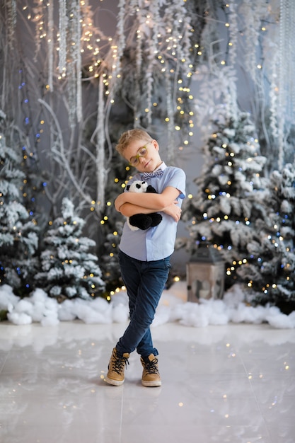 portrait of happy child boy with big glasses holding toy bear indoor studio