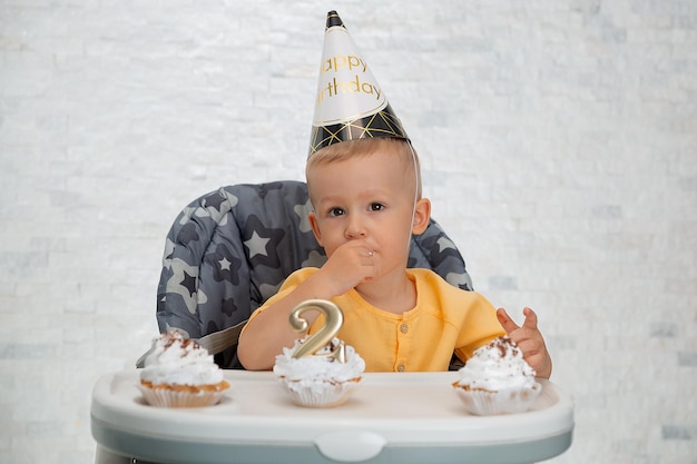 Portrait of happy child with cap and cake at his birthday