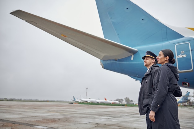 Ritratto di felice e fiducioso equipaggio di aeroplano caucasico vicino all'aereo