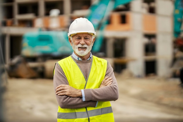 Portrait of a happy confident construction site manager standing at building area