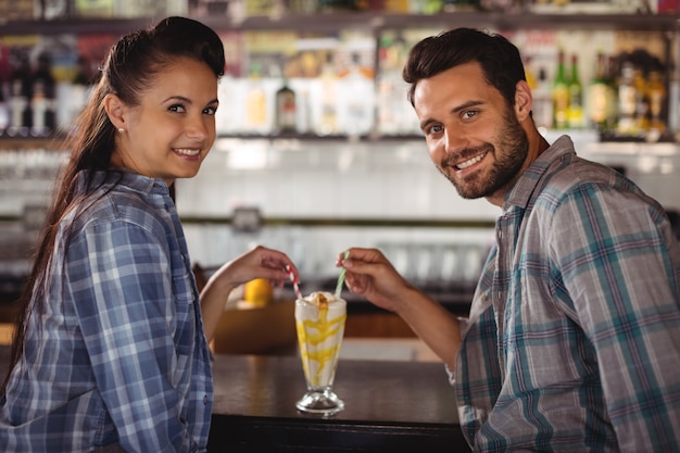 Портрет счастливой пары с молочным коктейлем за стойкой