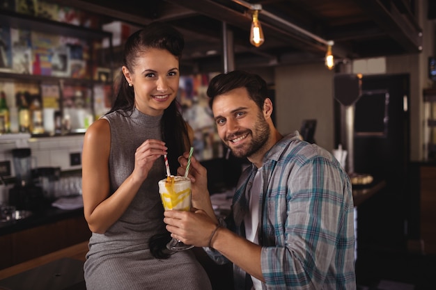 Portrait of happy couple having milkshake