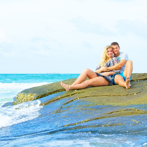 Portrait of happy couple in love sitting on the beach at summer day