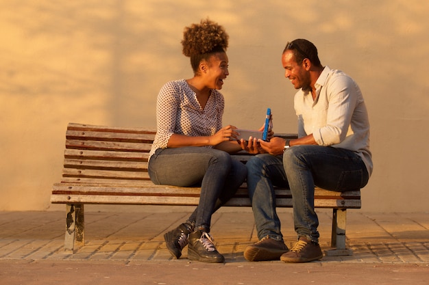 Portrait of happy couple sitting on bench with man giving anniversary gift