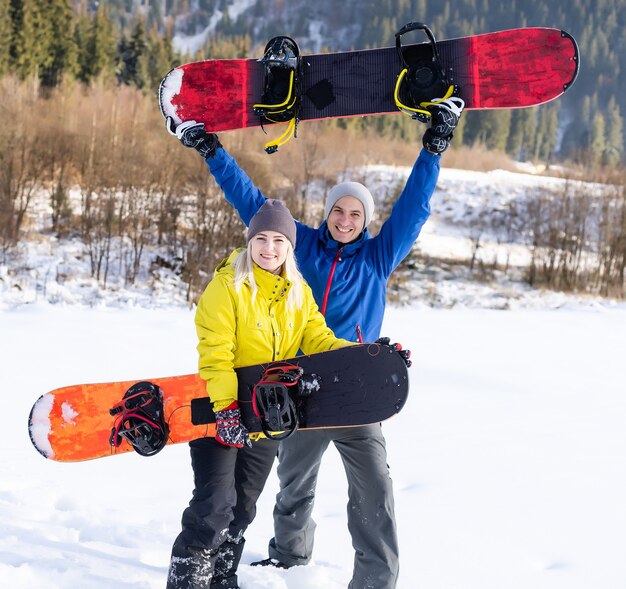 Portrait of happy couple of snowboarders outside during winter vacations