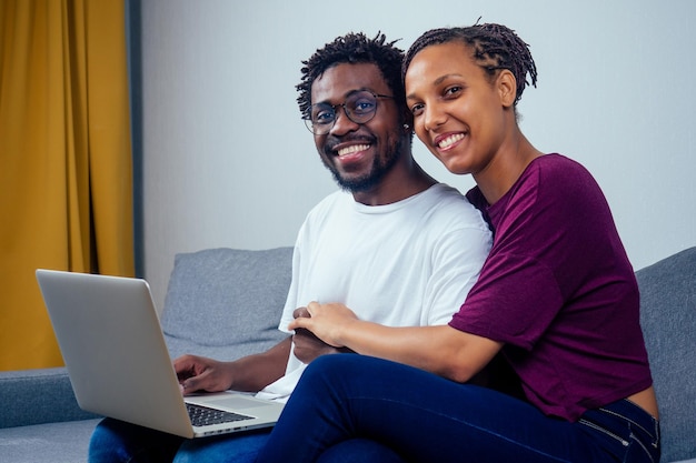 Portrait of an happy couple using a laptop computer in their house.