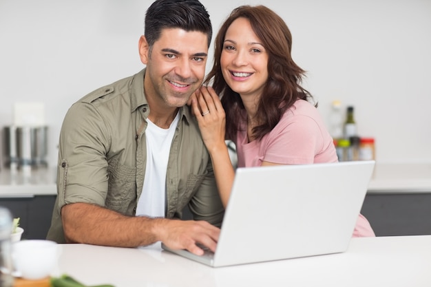 Portrait of a happy couple using laptop in kitchen