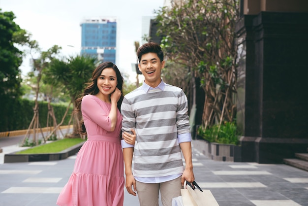 Portrait of happy couple with shopping bags after shopping in city