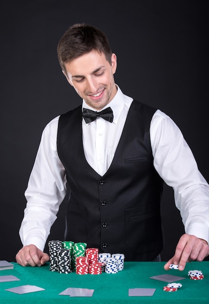 Il ritratto di un croupier felice sta tenendo le carte da gioco.