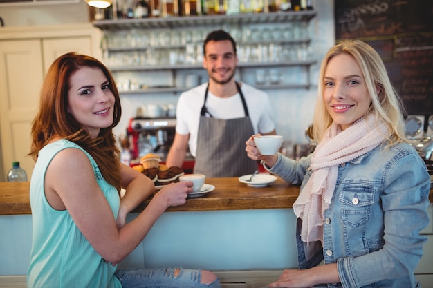 Portrait of happy customers with waiter at coffee shop