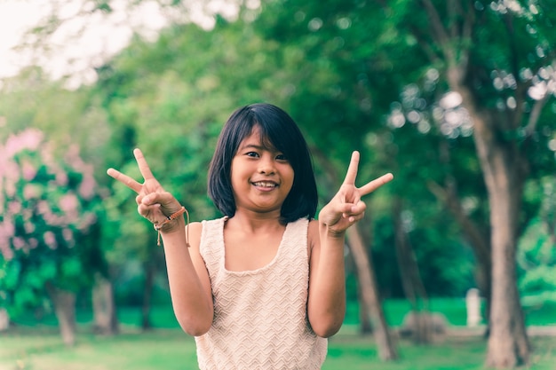 公園で様々なジェスチャーを示す幸せかわいいアジアの女の子の肖像画