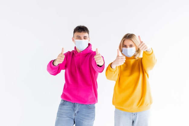 Portrait of happy cute lovers embracing on gray background holding medical safety sterile mask