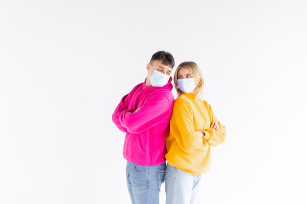 Portrait of happy cute lovers embracing on gray background holding medical safety sterile mask