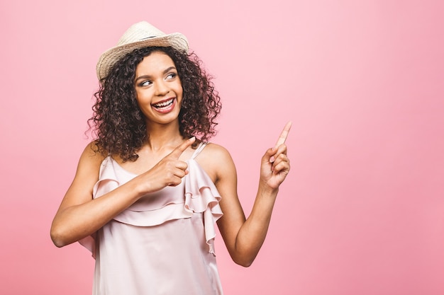 Portrait of happy dark skinned mixed race female model indicates with fore finger