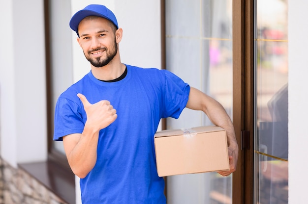 Portrait of happy delivery man holding box