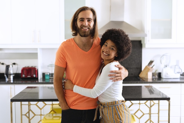 Portrait of happy diverse couple in kitchen smiling and embracing