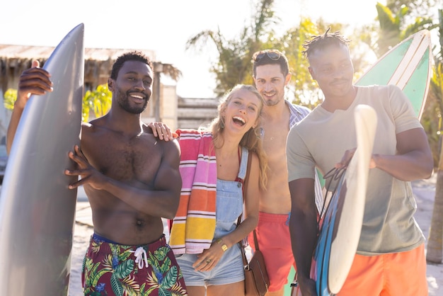 Photo portrait of happy diverse friends holding surfboards and smiling at beach, with copy space. spending quality time, lifestyle, friendship, summertime and vacation concept.