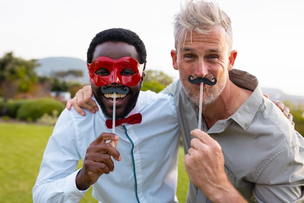 Portrait of happy diverse friends with fake moustache