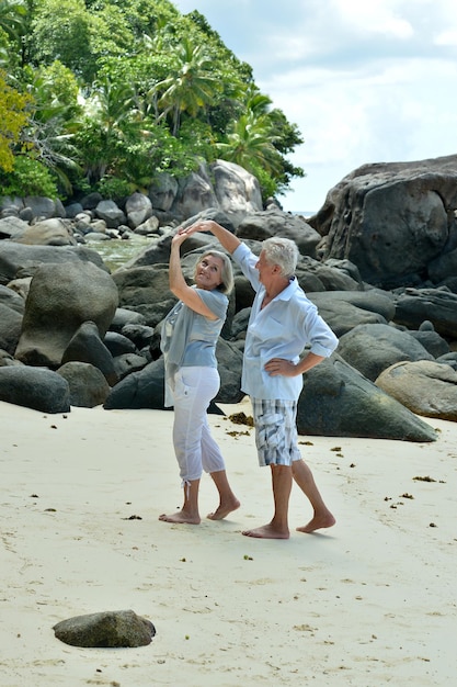 Portrait of happy elderly couple resting on beach dancing