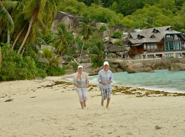 Portrait of happy elderly couple running on tropical beach