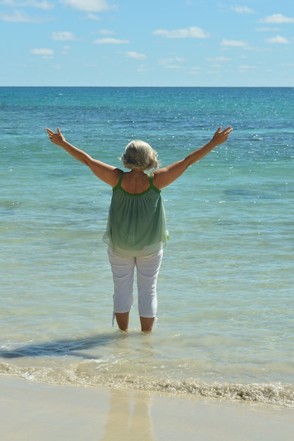 Portrait of a happy elderly woman on beach,back view