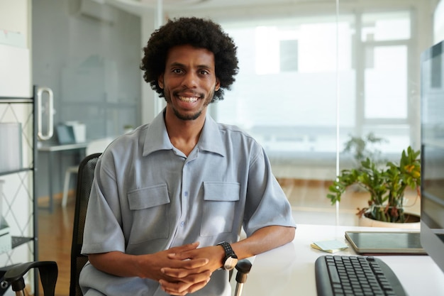 Portrait of happy entrepreneur sitting at office desk and smiling at camera