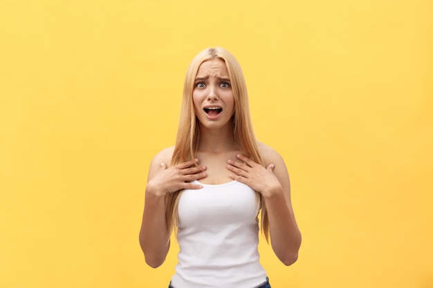 Portrait of a happy excited woman in white shirt with open mouth isolated over yellow background