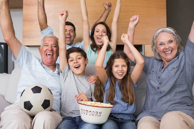 Портрет счастливой расширенной семьи смотреть телевизор в гостиной
