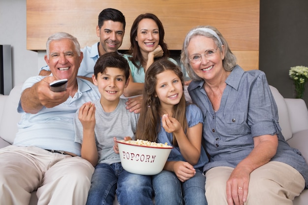 Portrait of happy extended family watching tv in living room