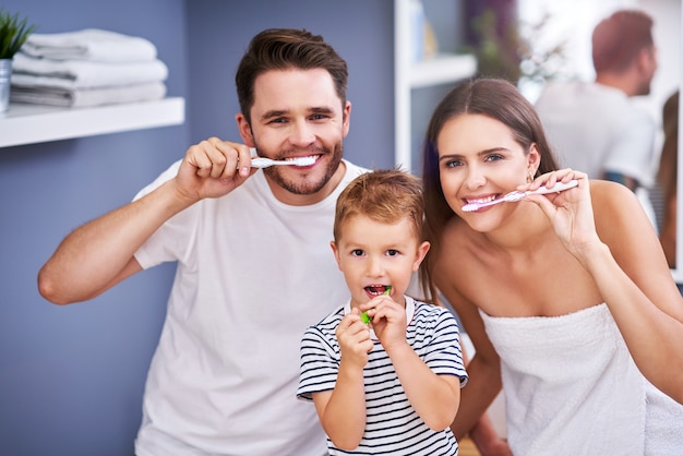 Ritratto di famiglia felice che si lava i denti in bagno