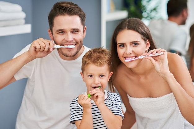 Portrait of happy family brushing teeth in the bathroom