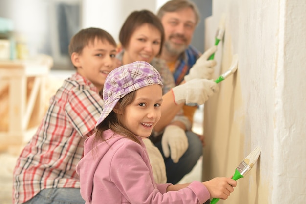 Foto ritratto di famiglia felice che fa la riparazione a casa e dipinge il muro