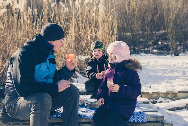 Photo portrait of a happy family enjoying picnic in winter forest