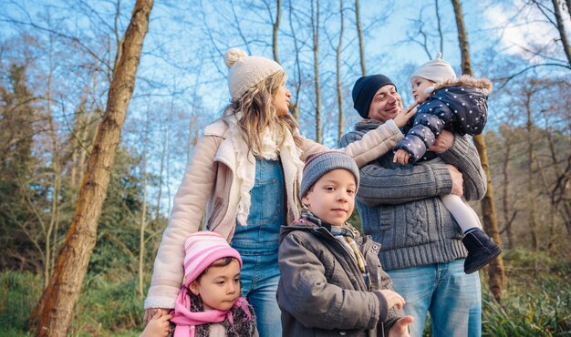 Portrait of happy family enjoying together leisure over a wooden pathway into the forest. Family time concept.