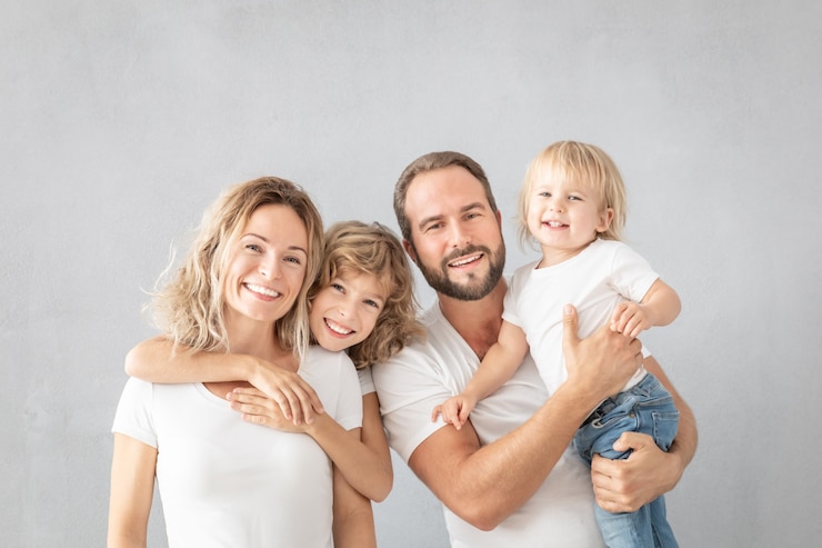Photo portrait of happy family - father, mother, daughter and son - against grey surface