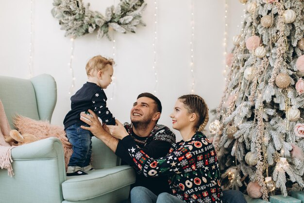 Portrait of happy family of father mother and little curly son celebrating Christmas together at home New Years Eve concept