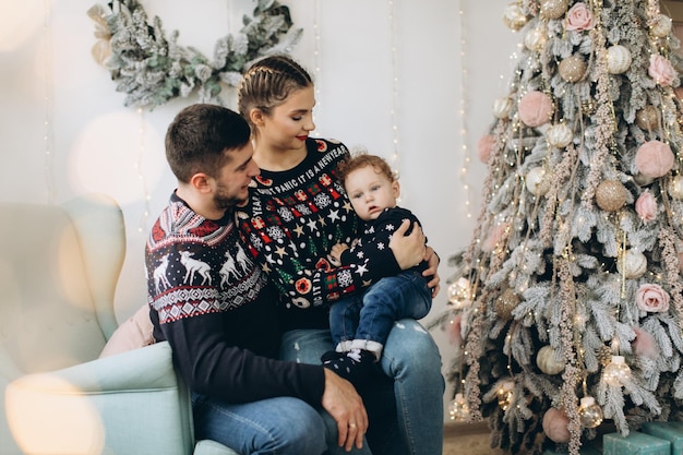 父母と自宅で一緒にクリスマスを祝う小さな巻き毛の息子の幸せな家族の肖像画大晦日のコンセプト