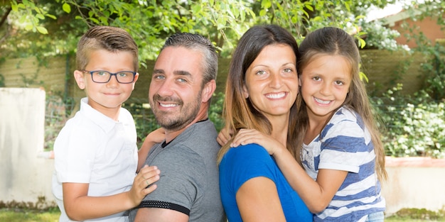 Ritratto di una famiglia di quattro felice nel parco del giardino della campagna