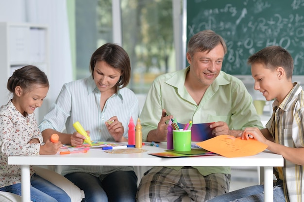 Portrait of happy family of four drawing together at home