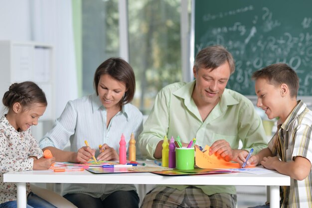 Portrait of happy family of four drawing together at home