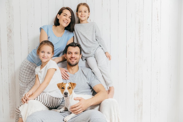 Portrait of happy family indoor Handsome father holds dog beautiful brunette mother and two daughters have fun together pose for family album spend time together People relationships concept