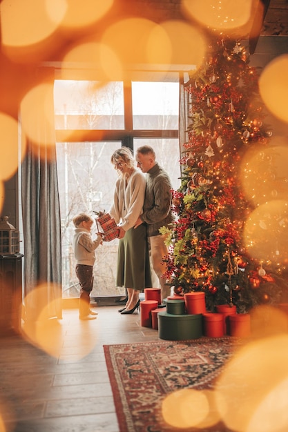 Foto ritratto di una famiglia felice in maglioni beige a maglia che aspetta babbo natale all'interno