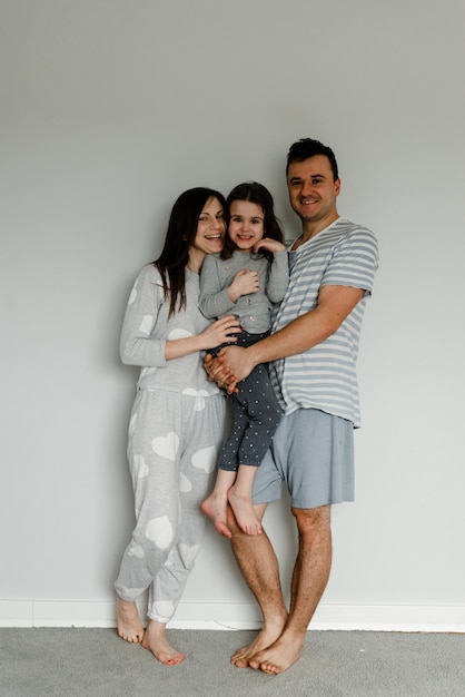 Portrait of a happy family in the morning,family in pajamas,family photo,happy young family posing in pajamas at camera,dad mom and daughter take a photo as a keepsake